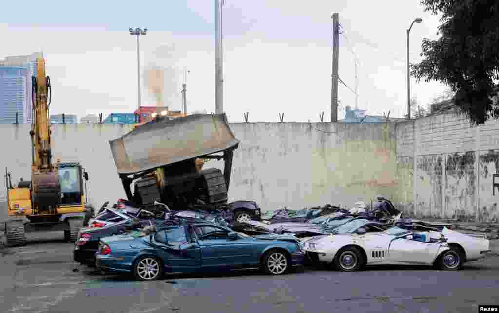 A bulldozer destroys smuggled luxury cars worth 61,626,000.00 pesos (approximately $1.2 million), which include used Lexus, BMW, Mercedes-Benz, Audi, Jaguar and Corvette Stingray, during the 116th Bureau of Customs founding anniversary in Metro Manila, Philippines