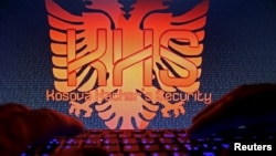 FILE - A man types in front of the logo of the "Kosova Hacker's Security" in this photo illustration. Ardit Ferizi, arrested in Malaysia on charges of stealing information on Americans, is thought to be a group leader.