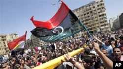 Egyptian protesters wave Libya's old national flag and an Egyptian flag as they demonstrate in the Tahrir square in Cairo, Egypt, April 10, 2011.