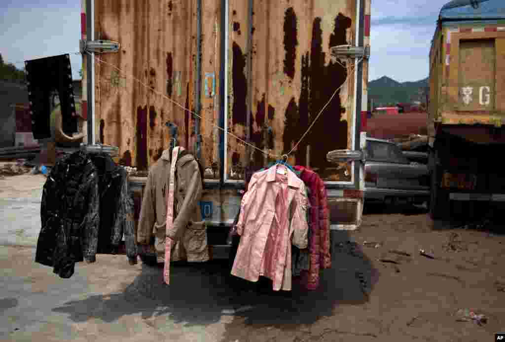Muddy clothes hang on a truck damaged by flood in a village in Fangshan district, Beijing, China, July 23, 2012.