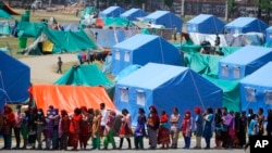 People who have had their homes damaged and are living in tents during the April 25 earthquake line up for drinking water and packaged noodles in Kathmandu, Nepal, May 3, 2015. 