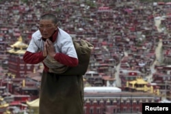 FILE - A Tibetan pilgrim prays near a Buddhist temple in Serthar County, Ganze Tibetan Autonomous Region, Sichuan province, China, July 20, 2015. The academy was founded in the 1980s among the mountains of the remote prefecture.