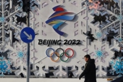 Seorang pria berjalan melewati instalasi Beijing 2022 jelang Olimpiade Musim Dingin Beijing 2022 di Beijing, China 25 Januari 2022. (Foto: REUTERS/Tyrone Siu)