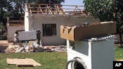 FILE: Farm workers clean up at Les de Jager's "Two Trees" farm in the Lions Den area, 150 kilometers north of Harare, Zimbabwe after looters ransacked the house, stripping the home and causing damage to farm equipment. The looters abandoned the washing machine on the lawn.