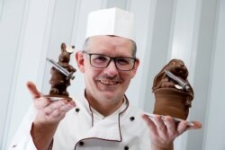 Laszlo Rimoczi berpose dengan dua karyanya di toko permen cokelatnya di Lajosmizse, Hungaria, 9 Maret 2021. (Foto: REUTERS/Bernadett Szabo)