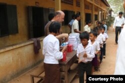 Im Chaem hands out gifts like books, pens and study tools to students during a donation events with US Christian missionary team in November 2017 near her home in O'Angre village, Anlong Veng district, Oddar Meanchey province. Photo by Pastor Touch Chanthou.