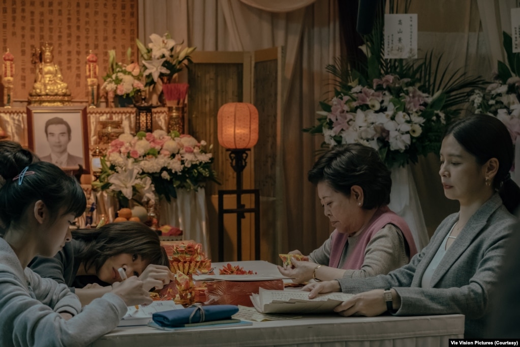 秀英阿嬷与女儿和孙女在灵堂里折纸莲花。（威视电影授权提供）(photo:VOA)