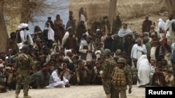 Afghan National Army soldiers keep watch as Afghans gather outside a U.S. base in Panjwai district Kandahar province, March 11, 2012. 