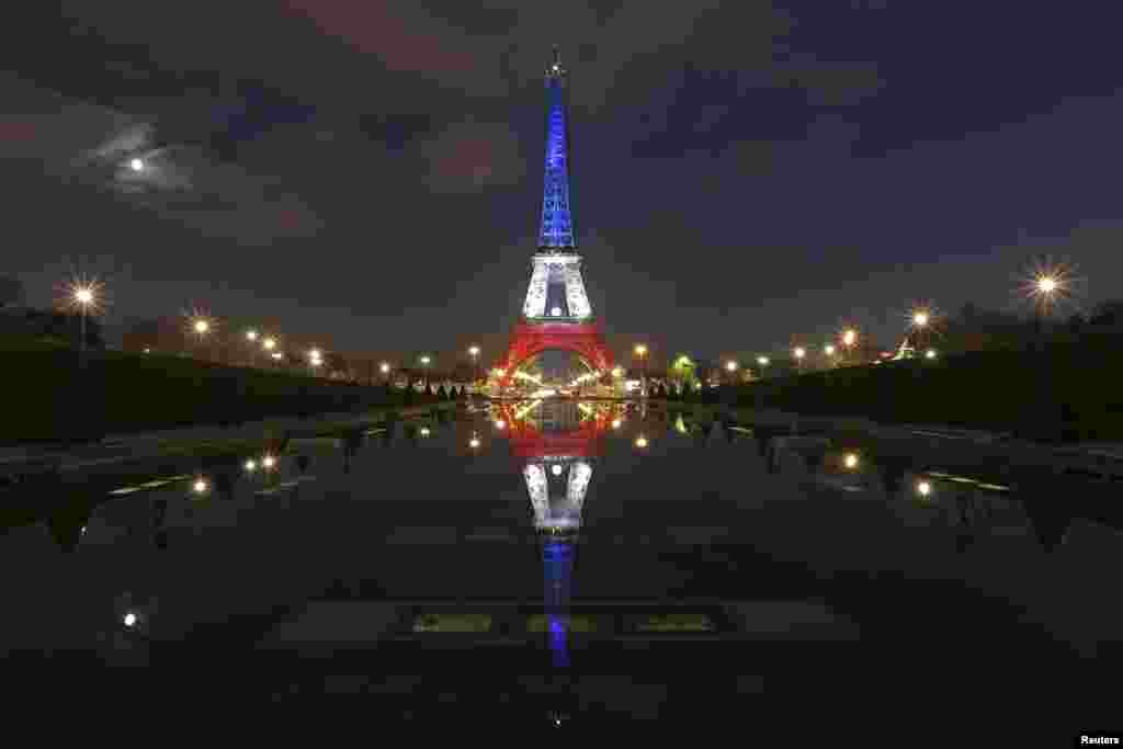 Menara Eiffel memancarkan warna biru, putih dan merah yang mewakili warna bendera Perancis dan dipantulkan di air mancur Trocadero di Paris, Perancis, 23 November 2015, sepuluh hari setelah sejumlah serangan maut terjadi di ibukota Perancis tersebut.