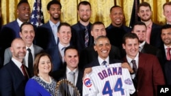 El presidente Barack Obama sostiene una camiseta personalizada de los Cachorros de Chicago que le regaló el equipo durante su visita a la Casa Blanca.