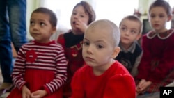 Lyuba, center, wearing a red outfit, sits along with other girls in a children's home in Khartsyzk, Ukraine, March 7, 2015.