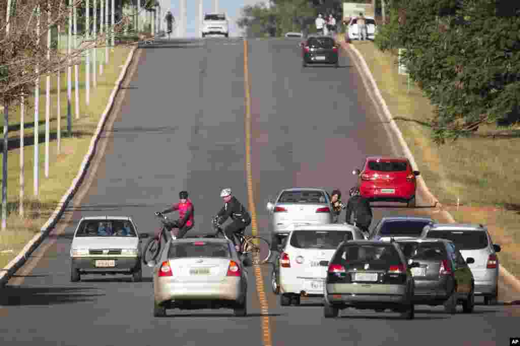 Brazil&#39;s President Dilma Rousseff is surrounded by cars as she rides her bicycle followed by security guards near Alvorada Palace, the presidential residence, in Brasilia.