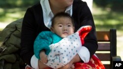 Seorang ibu mengasuh bayinya di sebuah taman di Beijing, China (30/10). China mengatakan kebijakan satu anak di negara itu masih tetap berlaku untuk saat ini.
