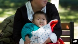 A child is wrapped up against the cold at a park in Beijing, China, Oct. 30, 2015. Shares of companies making diapers, baby strollers and infant formula got a boost Friday from China's decision to scrap its one-child policy.