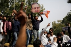 Activists of India's opposition Congress party's youth wing shout slogans against the ruling Bharatiya Janata Party (BJP) as one of them holds a head from a cut out photograph of billionaire jeweler Nirav Modi in New Delhi, India, Feb. 16, 2018.
