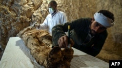 Des archéologues égyptiens restaurent une momie enveloppée dans du lin, trouvée à la tombe "Kampp 150" de la nécropole de Draa Abul Naga, sur la rive ouest du Nil, au sud de la ville égyptienne de Louxor, à environ 650 kilomètres au sud de la capitale, le