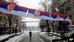 FILE - Workers hang Serbian flags in the northern, Serb-dominated part of ethnically divided town of Mitrovica, Kosovo, Dec. 14, 2018.