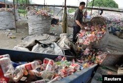 중국 안후이성 허페이의 재활용 쓰레기 처리시설에서 작업자가 플라스틱병을 쏟아붓고 있다.