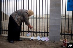 FILE - Kareema Abdul-Khabir, who teaches special needs students at an elementary school in Barstow, Calif., places some cards made by her students at a makeshift memorial honoring the victims of a shooting rampage, in San Bernardino, Dec. 4, 2015