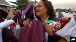 Laquetta Smith, right, gives a congratulatory hug to Lauryn Scott, after the Kalamazoo Central High School graduation ceremony on June 7, 2006, in Kalamazoo, Mich. Kalamazoo Central was the first graduating class to qualify for the Kalamazoo Promise. (AP Photo/Mark Bialek)