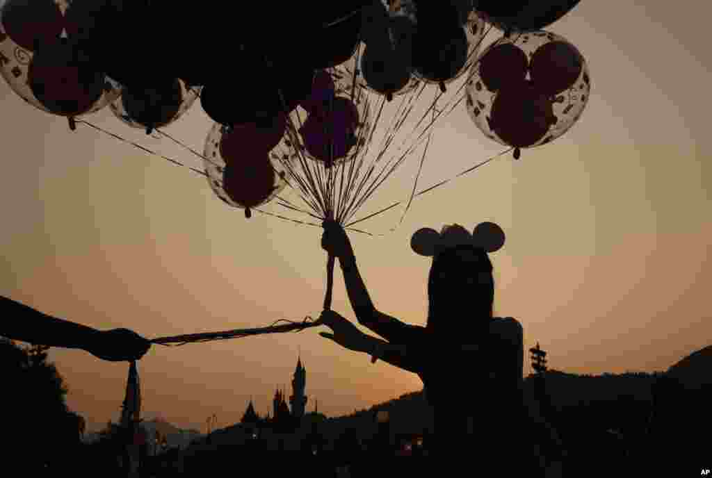 A Mickey Mouse fan hold balloons in front of the Sleeping Beauty Castle at the Hong Kong Disneyland. Hong Kong Disneyland is celebrating it's 10th anniversary.