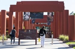 FILE - Students walk past the Harriet and Charles Luckman Fine Arts Complex at the The Cal State University, Los Angeles campus Thursday, April 25, 2019. (AP Photo/Damian Dovarganes)