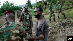 FILE - Congolese M23 rebel fighters detain a man they suspect to be an FDLR (Force Democratique de Liberation du Rwanda) rebel returning from an incursion into Rwanda Near Kibumba, north of Goma, Nov. 27, 2012. 