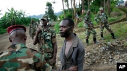 FILE - Congolese M23 rebel fighters detain a man they suspect to be an FDLR (Force Democratique de Liberation du Rwanda) rebel returning from an incursion into Rwanda Near Kibumba, north of Goma, Nov. 27, 2012. 
