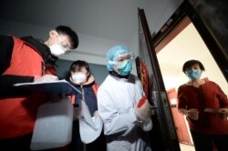 中国天津的社区工作人员和医疗人员挨门挨户地检查居民健康状况。（2020年2月12日）