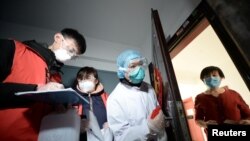 资料照片:中国天津的社区工作人员和医疗人员挨门挨户地检查居民健康状况。（2020年2月12日）