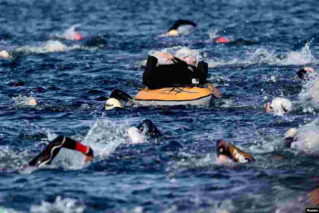 Peder Mondrup, 34, is seen on a rubber boat being pulled by his twin brother Steen as they compete in the swimming portion of the KMD Ironman Copenhagen challenge, Denmark, Aug. 24, 2014.