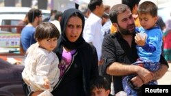 A family fleeing the violence in the Iraqi city of Mosul waits at a checkpoint in outskirts of Arbil, in Iraq's Kurdistan region, June 10, 2014. 