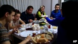 On the first day of the Muslim holy month of Ramadan, Selami Aykut, 38, center, and his family observe the sahoor traditional breakfast of Ramadan, in Istanbul, after being woken by street drummers early Monday, June 6, 2016. 