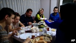 On the first day of the Muslim holy month of Ramadan, Selami Aykut, 38, center, and his family observe the sahoor traditional breakfast of Ramadan, in Istanbul, after being woken by street drummers early Monday, June 6, 2016.