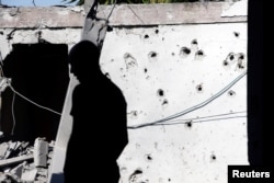 A man is silhouetted as he stands near a house damaged by a rocket fired from the Gaza Strip, in the Israeli city of Ashkelon, Nov. 13, 2018.