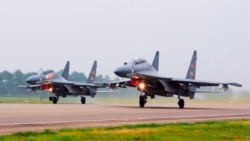 FILE - In this undated file photo released by China's Xinhua News Agency, two Chinese SU-30 fighter jets take off from an unspecified location to fly a patrol over the South China Sea.