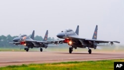 FILE - In this undated file photo released by China's Xinhua News Agency, two Chinese SU-30 fighter jets take off from an unspecified location to fly a patrol over the South China Sea.