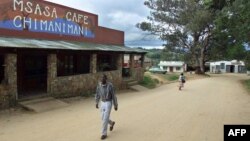 FILE - A man passes the local cafe as a woman and her child cross the main street in the village of Chimanimani some 420 km southeast of Harare, May 18, 2000.