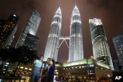 Wisatawan berfoto cinderamata di gedung ikonik Malaysia, Menara Kembar Petronas di Kuala Lumpur, Malaysia, Kamis, 14 Januari 2016. (Foto: AP)