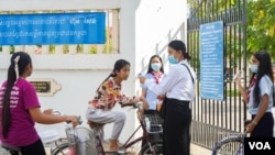 Students volunteer to take the temperature of other students and visitors entering the school ground to prevent the spread of COVID-19, in Phnom Penh, Cambodia, September 2020. (Khan Sokummono/ VOA Khmer)
