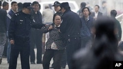 Police officers take away a female petitioner from a court house, where jailed activist Wang Lihong attends her court appeal case on charges of creating a disturbance when she helped lead a protest on behalf of three bloggers, in Beijing, China, Thursday,