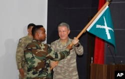 Turkish Chief of Staff General Hulusi Akar, right, hands a flag to a Somali soldier at the new Turkey-Somali military training center in Mogadishu, Sept. 30, 2017.