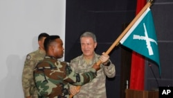 FILE - Turkish Chief of Staff General Hulusi Akar, right, hands a flag to a Somali soldier at the new Turkey-Somali military training center in Mogadishu, Sept. 30, 2017.