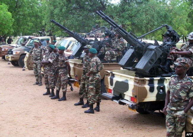 FILE - This photo taken June 17, 2014 shows Cameroonian soldiers standing next to pick up trucks with mounted heavy artillery in Mora, northern Cameroon.