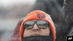 A Chicago Bears fan watches in the snow during an NFL football game against the Cleveland Browns in Chicago, Dec. 24, 2017. 