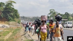 Residents of the popular district of Abobo, a suburb of Abidjan, flee the quarter carrying their luggage on their heads, February 25, 2011