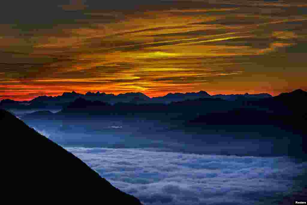 Fog covers the Inntal valley as the sunrise is seen from Hundskopf mountain in the western Austrian village of Gnadenwald, Austria.