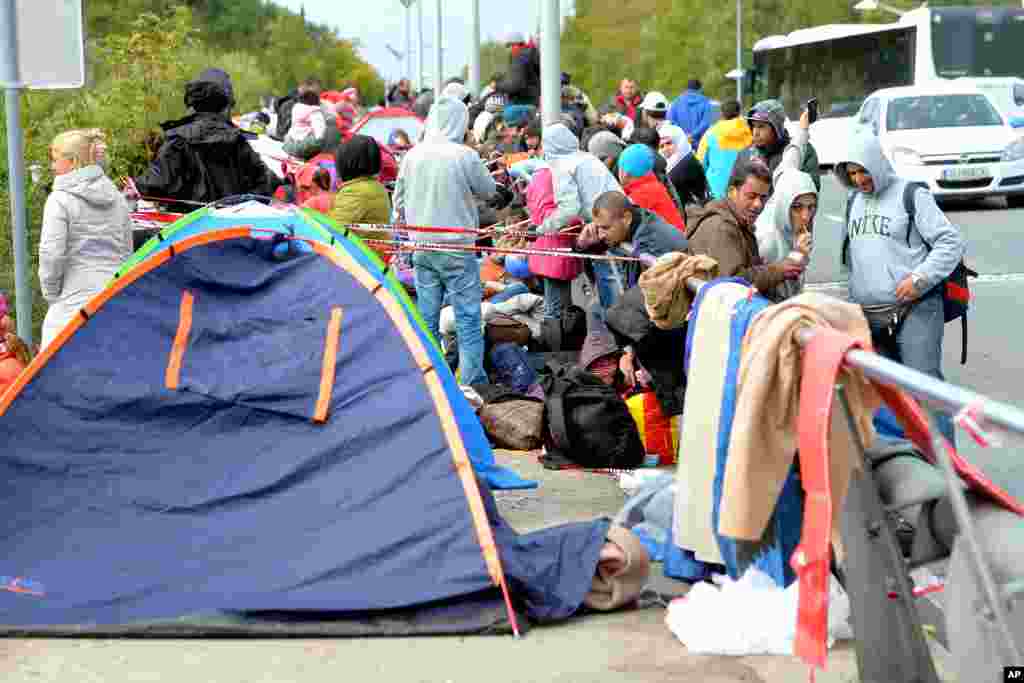 Migrants wait on a bridge for their registration and transport by German police to a refugee shelter, in Salzburg, Austria at the border to Germany. Chancellor Angela Merkel said the potential benefits resulting from the influx of migrants and refugees far outweighs any dangers.