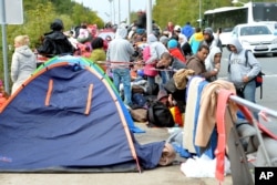 FILE - Migrants wait on a bridge for their registration and transport by German police to a refugee shelter, Sept. 24, 2015 in Salzburg, Austria at the border to Germany.