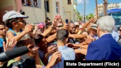 El secretario de Estado John Kerry saluda a cubanos frente a la Embajada de EE.UU. en La Habana, reabierta este viernes